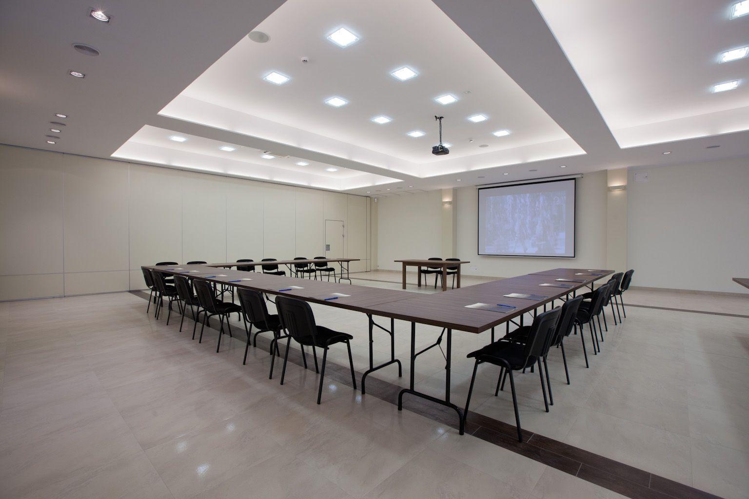 Sala konferencyjna z projektorem i stołami ułożonymi pośrodku